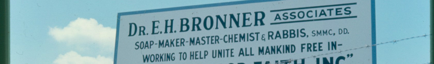 Sign reads Dr. E.H. Bronner Associates. Soap Maker Master Chemist Rabbis, SMMC, DD. Working to help unite all mankind free in against a clear sky, promoting Dr. Bronners sustainable, eco friendly mission