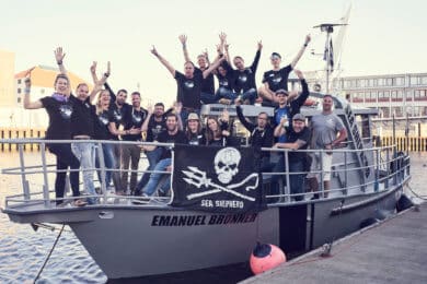 A group of people cheering on the Emanuel Bronner ship