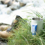 Travel-size toothpaste in the grass next to a boot