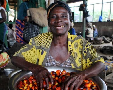 Woman worker posing with a bucket of palm kernels