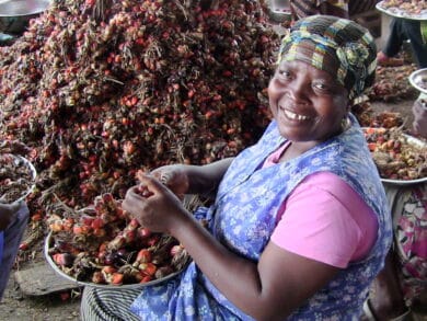 A woman posing for a photo with palm fruit