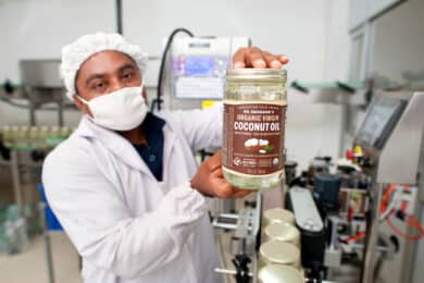 Serendipol worker holding a jar of Dr. Bronner's Organic Virgin Coconut Oil